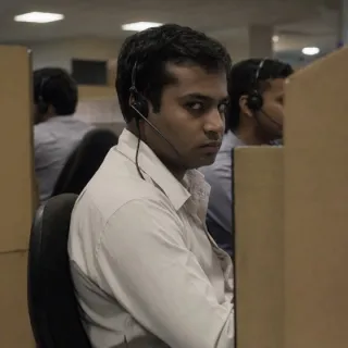 A man in a call centre cubicle wearing a headset