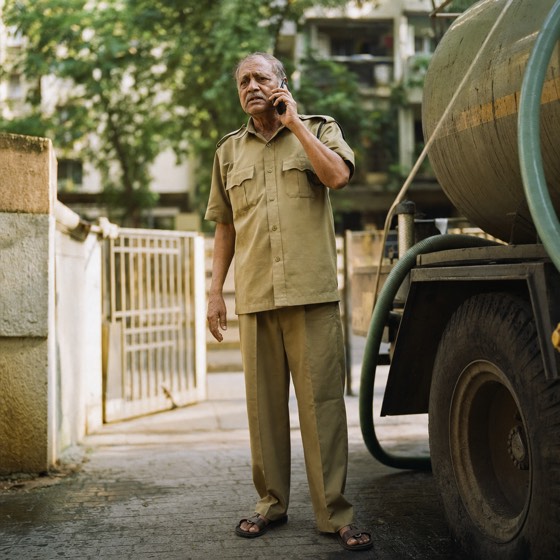 A society watchman standing beside a water tanker
