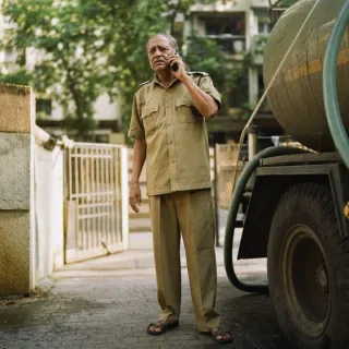 A society watchman standing beside a water tanker