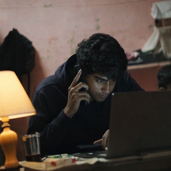 A man running a phone scam from a dim room